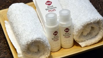 Una bandeja de madera con dos toallas blancas enrolladas y dos botellas de loción corporal Best Western PLUS.