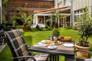 An outdoor dining area with a table set for breakfast, surrounded by chairs and potted plants. - Best Western Plus Delta Park Hotel (Mannheim)