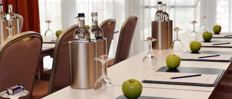 A conference room with a long table, chairs, and various items like bottles, glasses, and apples.