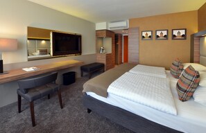 A hotel room with a bed, a desk, a chair, a TV, and a wardrobe. - Best Western Plus Delta Park Hotel (Mannheim)