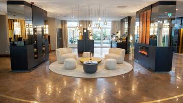 A hotel lobby with a central seating area, a reception desk, and a fireplace.
