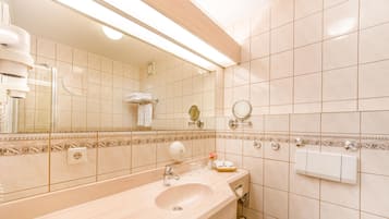 Ein Badezimmer mit Waschbecken, Spiegel, Handtuchhalter und einem fest installierten Heizkörper.