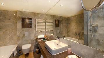 A modern bathroom with a large mirror, a bathtub, a toilet, and a shower.