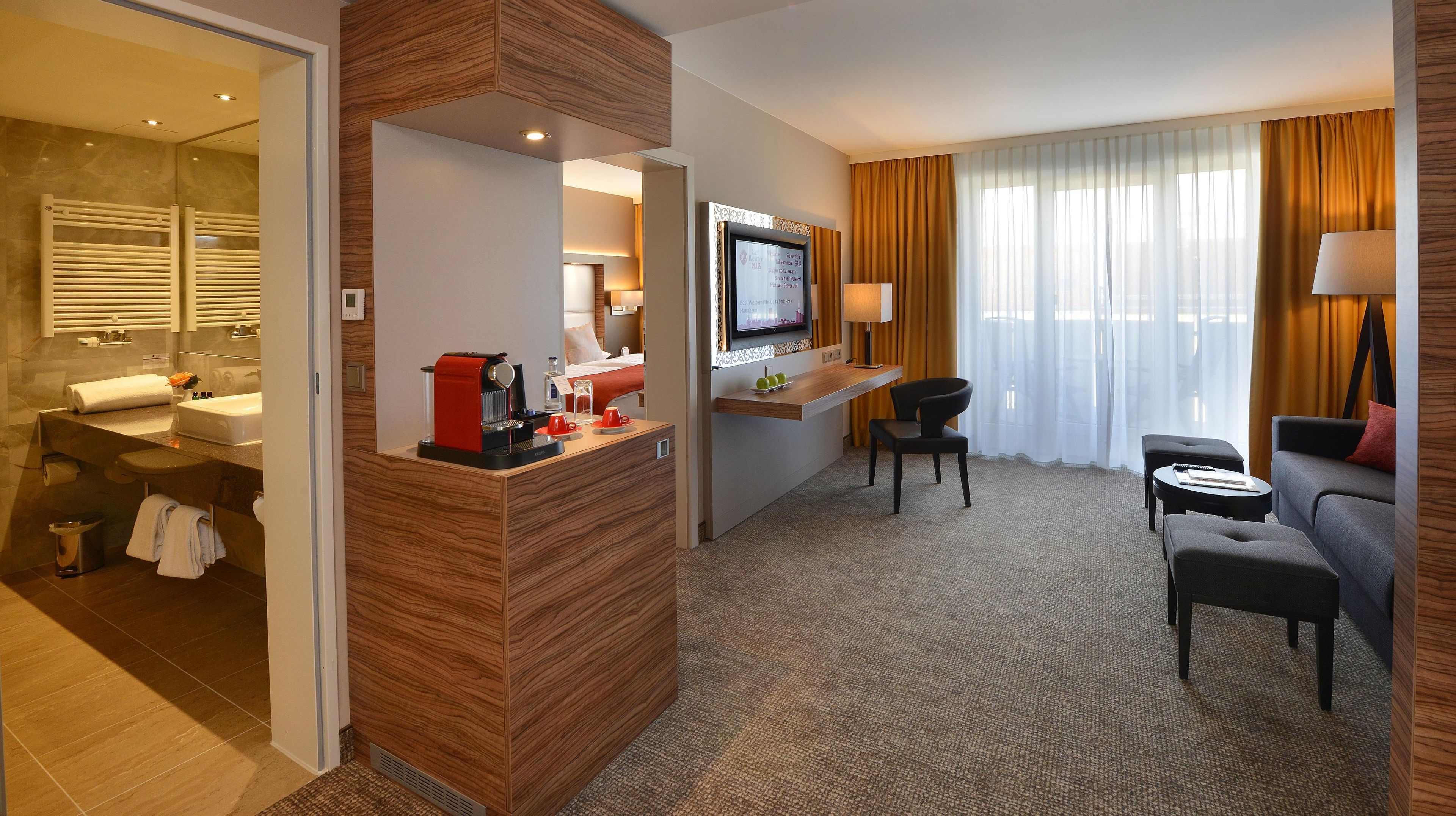 A hotel room with a bathroom, a seating area, and a TV.
