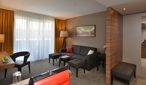A hotel room with a sofa, armchairs, a small table, a lamp, and a painting on the wall. - Best Western Plus Delta Park Hotel (Mannheim)