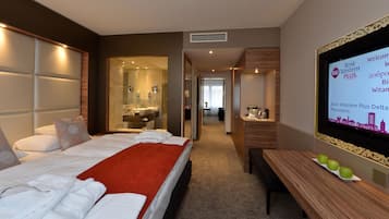 Ein Hotelzimmer mit Bett, Bad, Schreibtisch und Fernseher, der Auszeichnungen zeigt.