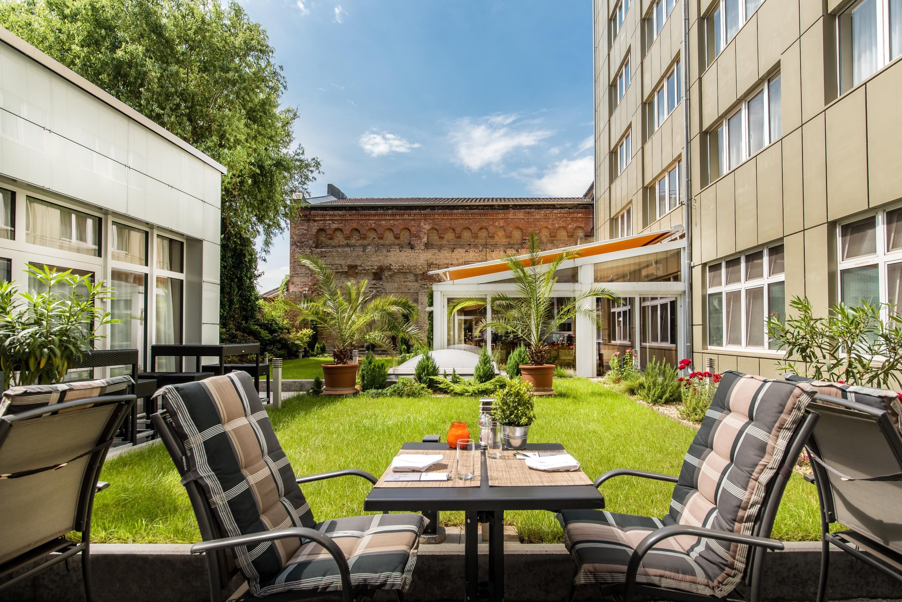 A courtyard with outdoor seating, a brick building, and greenery.