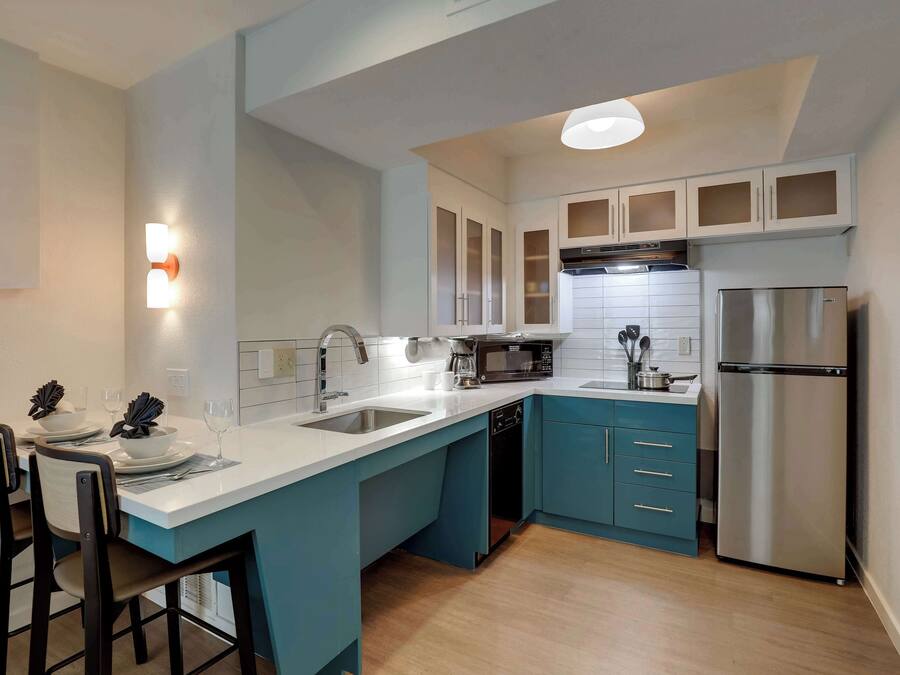 Una cocina moderna con una isla central, armarios blancos y electrodomésticos de acero inoxidable.