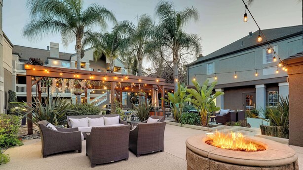 An outdoor seating area with wicker furniture, a fire pit, and string lights.