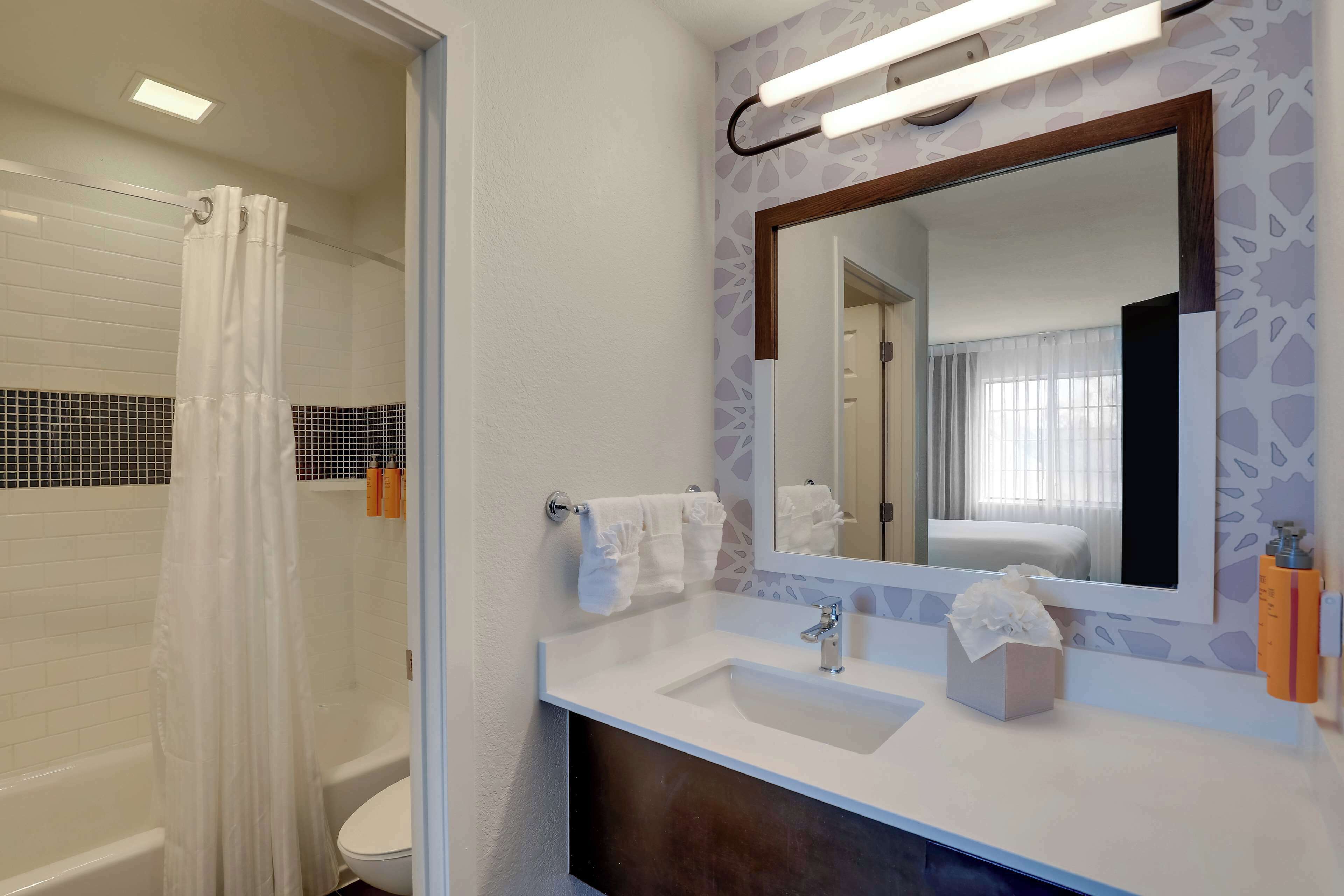 A bathroom with a bathtub, a toilet, a sink, a mirror, and a shower curtain.