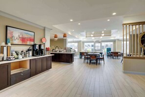 Een ruime keuken met een centraal eiland, een eethoek met houten stoelen en een trap met een houten leuning.