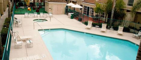 A swimming pool with lounge chairs and umbrellas, surrounded by buildings with tiled roofs.