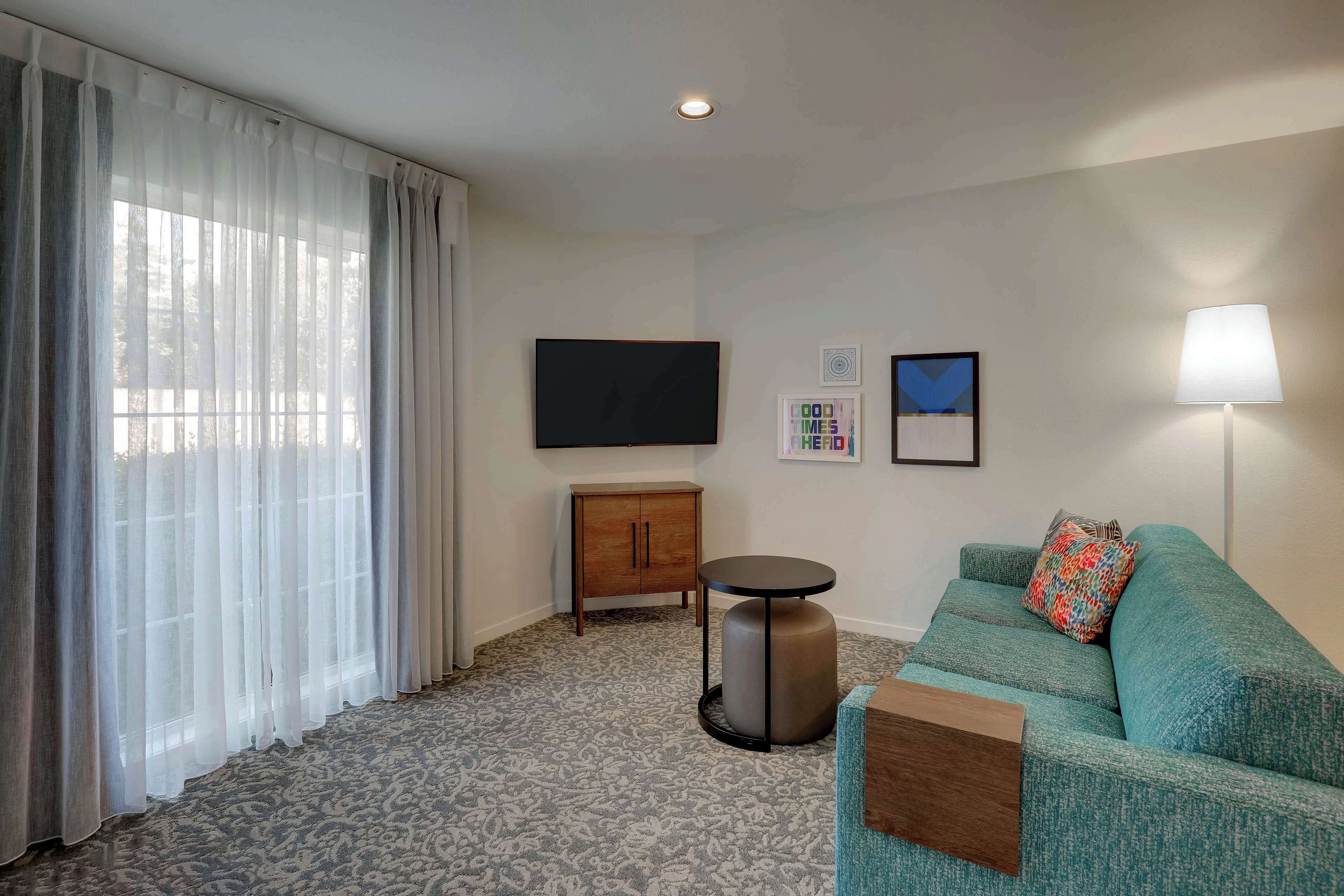 Uma sala de estar moderna com sofá, uma mesa pequena, um armário e uma TV de tela plana.