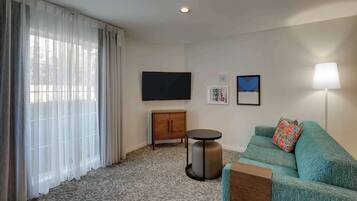 Uma sala de estar moderna com sofá, uma mesa pequena, um armário e uma TV de tela plana.