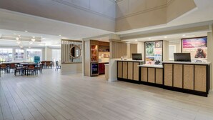 A spacious lobby with a reception desk, seating area, and a view of the outside.