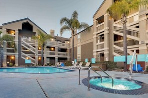 Een hotel met een zwembad, een jacuzzi en een trap naar de bovenverdiepingen.