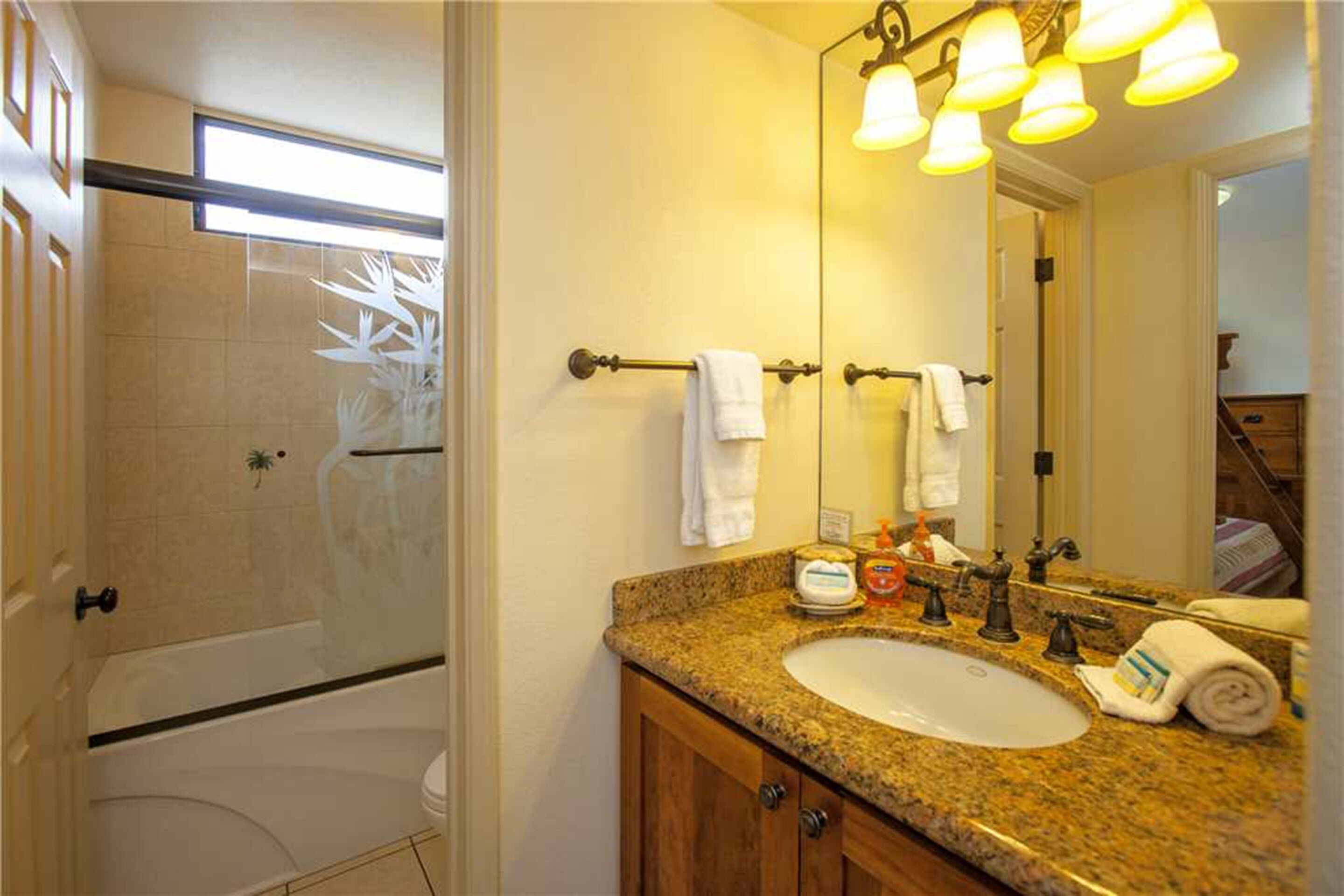 A bathroom with a granite countertop sink, a large mirror, and a shower area.