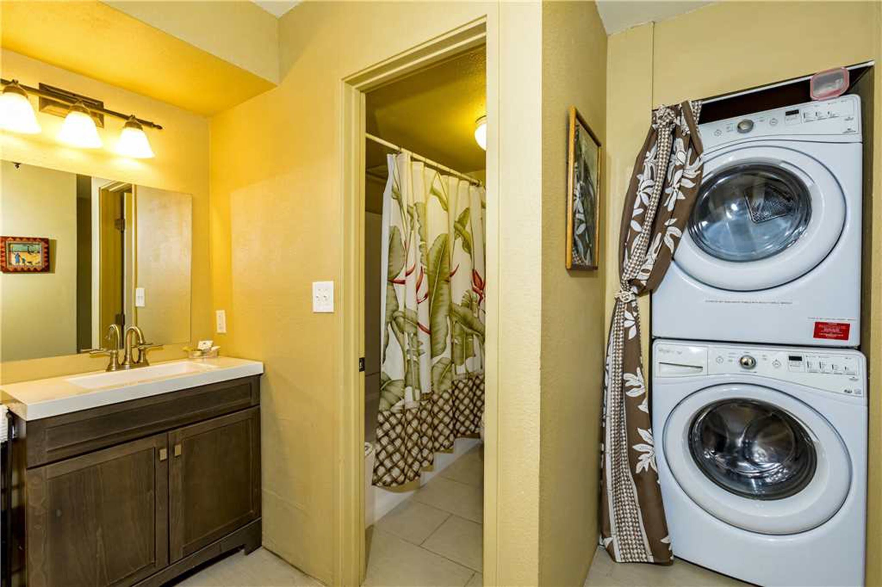 A bathroom with a sink, mirror, and a washing machine.