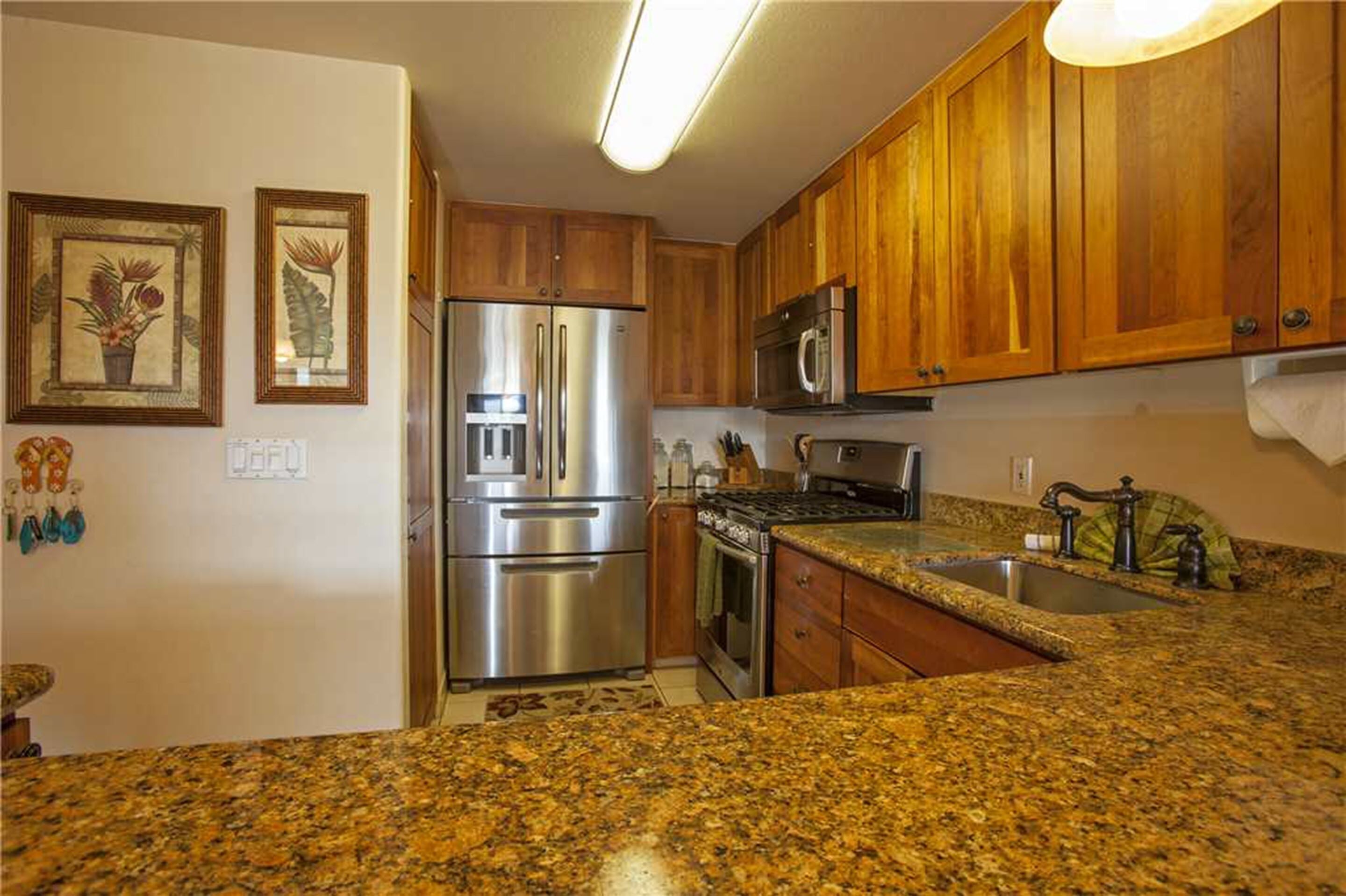 A kitchen with wooden cabinets, stainless steel appliances, granite countertops, and a microwave.