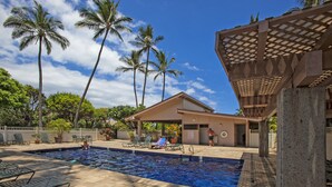 A swimming pool with lounge chairs, palm trees, and a covered area with a pergola. - Kihei Akahi - Maui Condo & Home (Kihei)