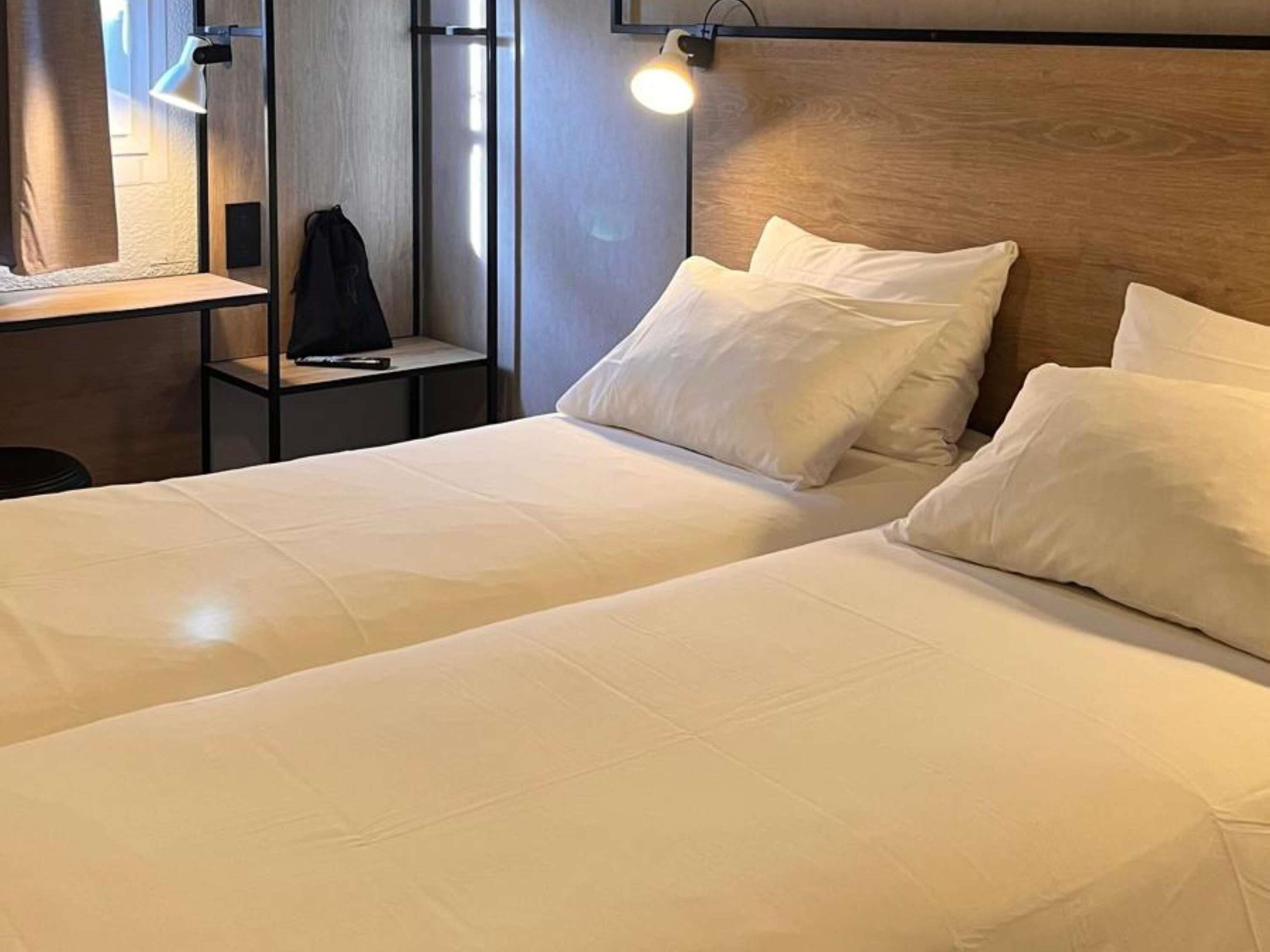 A hotel room with two beds, a desk, and a chair.