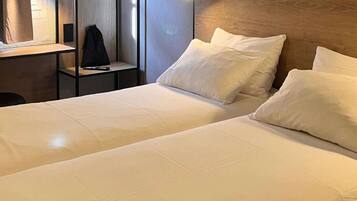 A hotel room with two beds, a desk, and a chair.