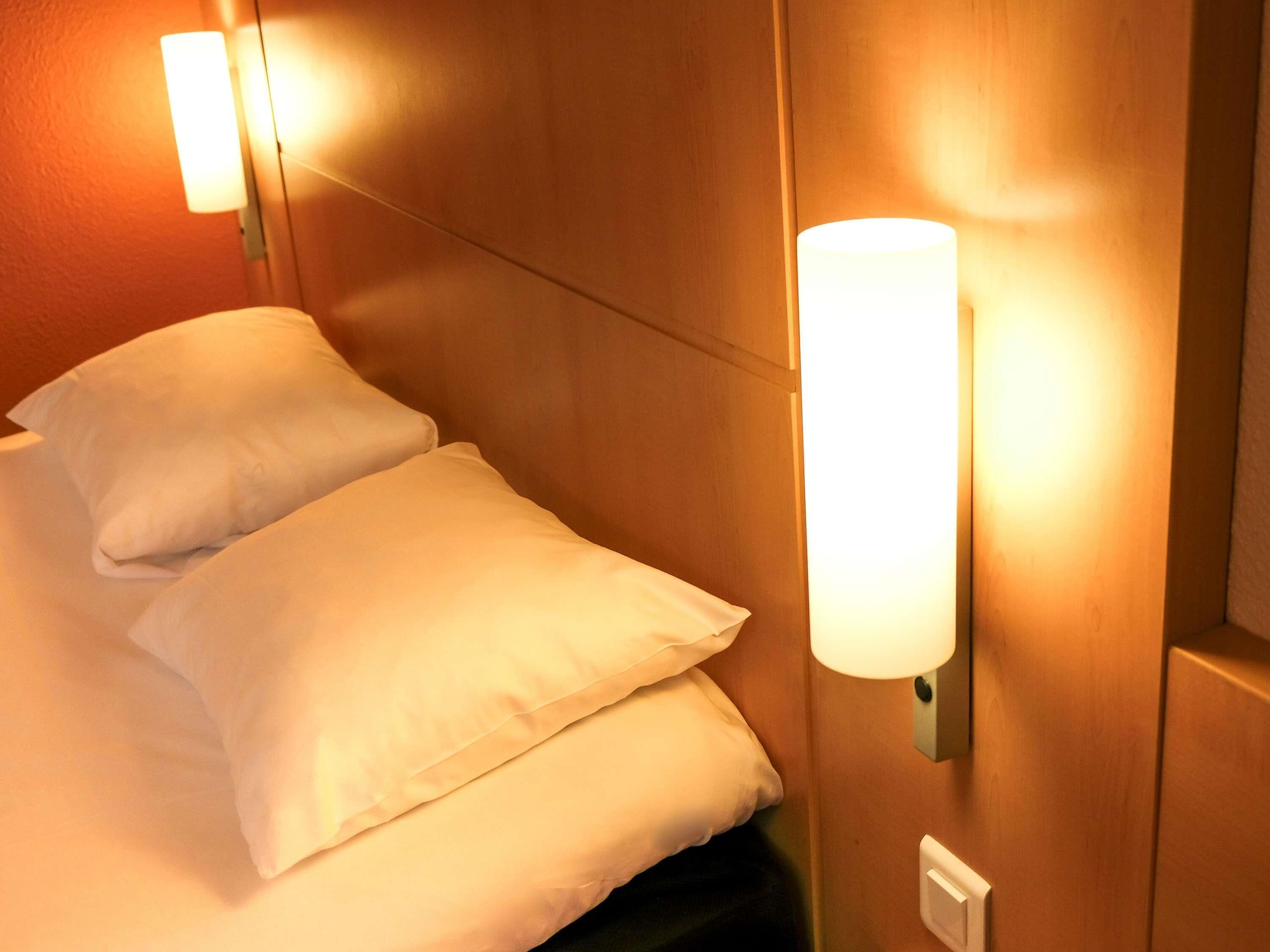 Ein Hotelzimmer mit einem Bett, zwei Kissen und Wandleuchten.