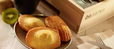 A plate of fried pastries, a cup of coffee, and a wooden box labeled "ibis kitchen".