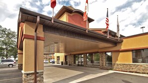 A hotel entrance with a covered walkway, stone pillars, and flags. - Quality Inn (Kitchener)