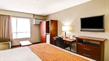 A hotel room with a bed, a desk, a chair, a television, and a wardrobe.