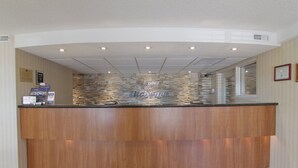 A reception area with a wooden counter, a stone wall, and a sign that reads "Welcome to Kitchen." - Quality Inn (Kitchener)