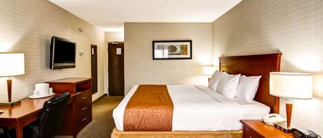 Una habitación de hotel con cama, escritorio, silla, televisor y teléfono.