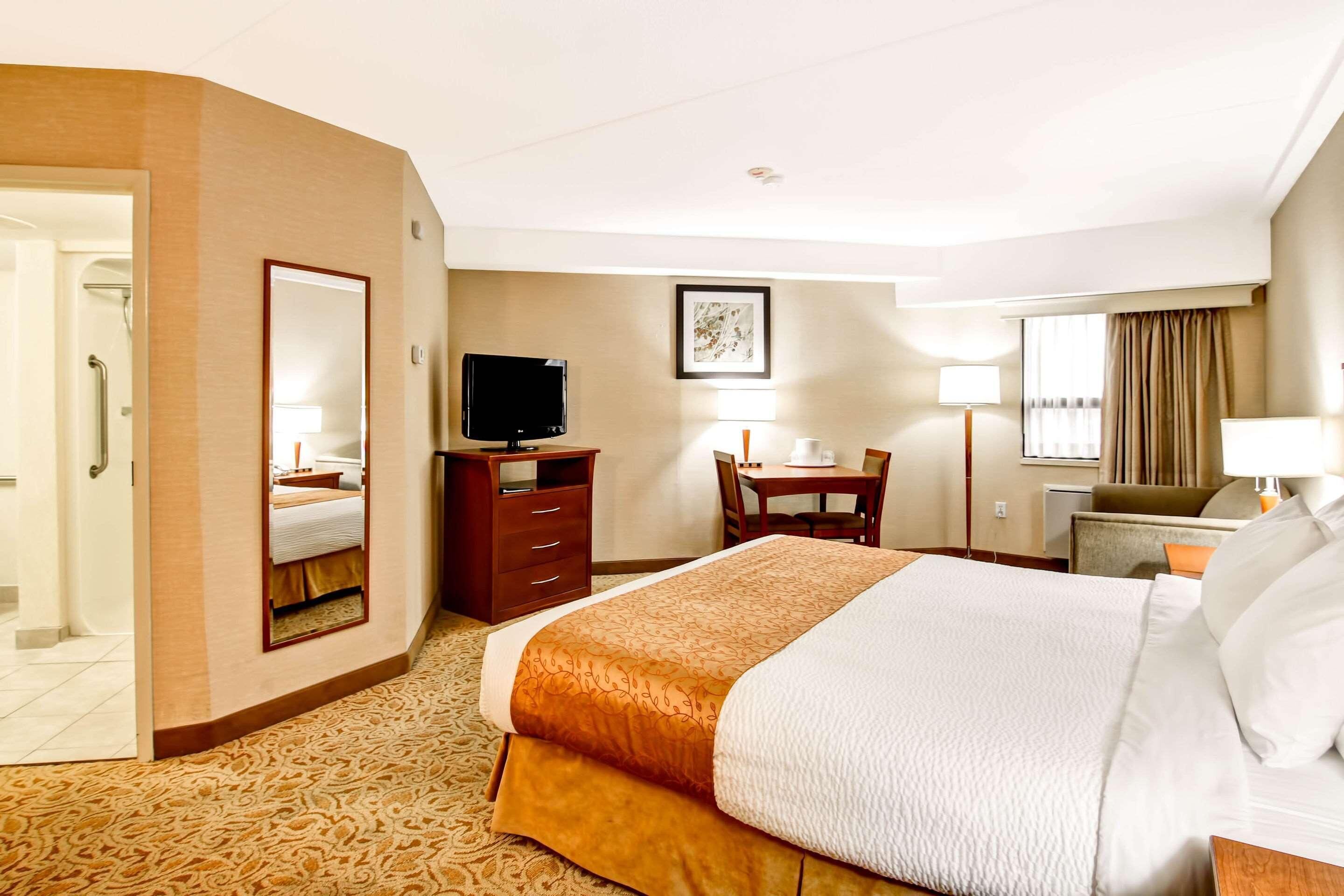 A hotel room with a bed, a desk, a television, a chair, and a window with curtains.