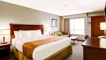 Een hotelkamer met een groot bed, een bureau, een stoel en een televisie.