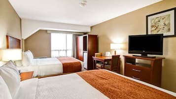 Habitación de hotel con dos camas, un escritorio, un televisor y una ventana con cortinas.