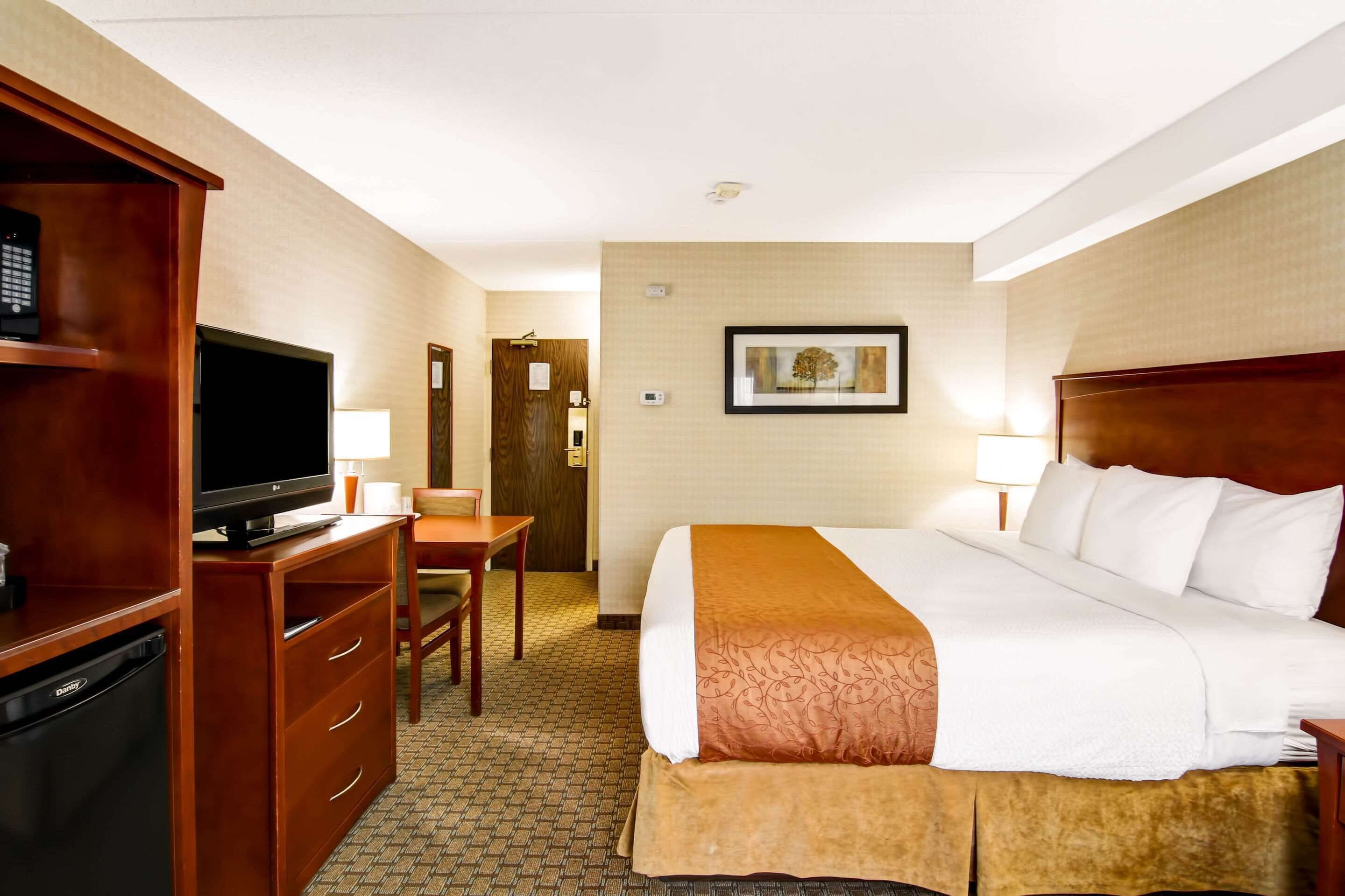 Una habitación de hotel con cama, televisión, escritorio y armario.