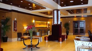 A spacious lobby with a central reception desk, a large pillar, and a seating area with round tables. - Northern Hotel (Billings)