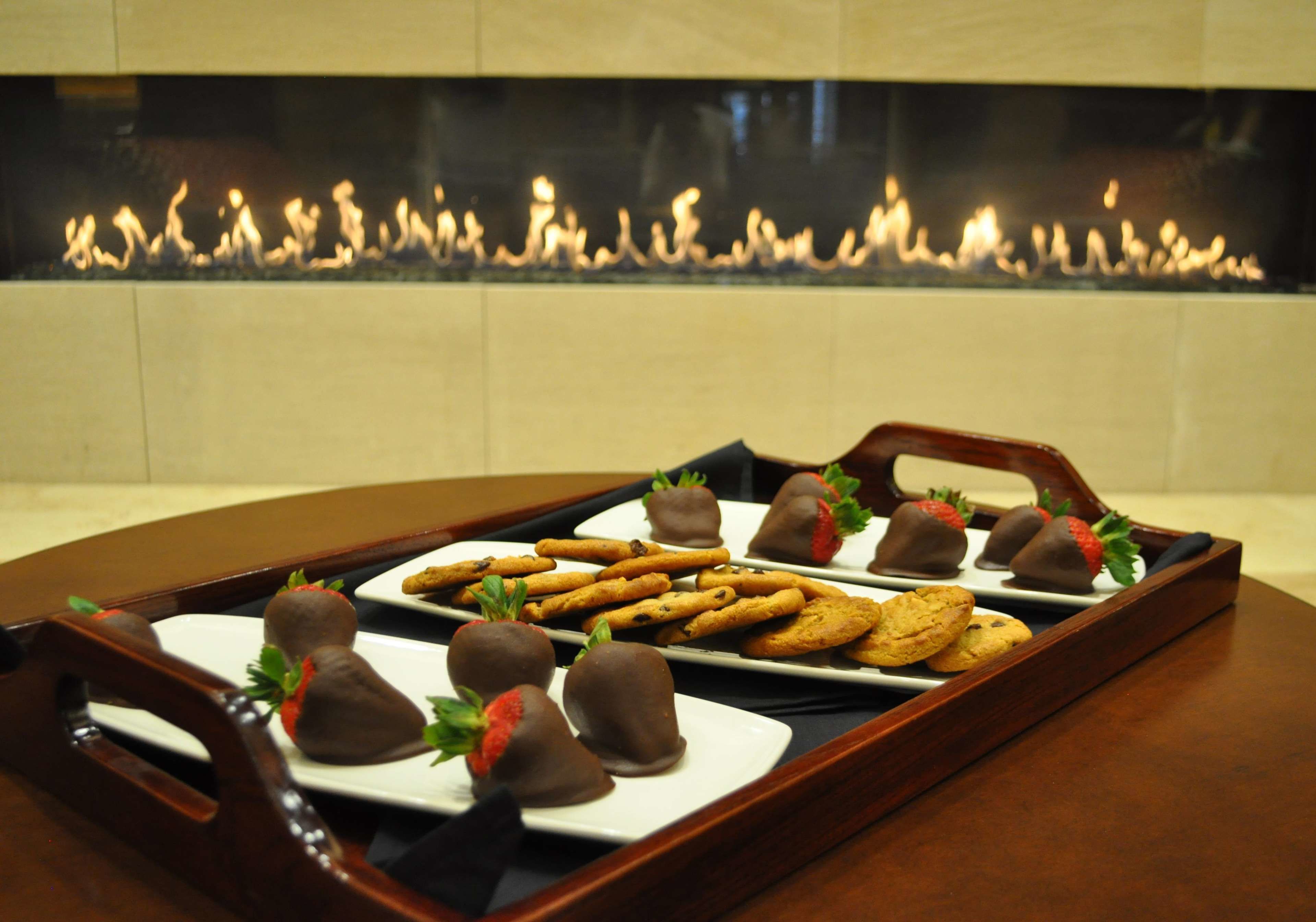 A tray of chocolate-covered strawberries and cookies on a wooden tray.