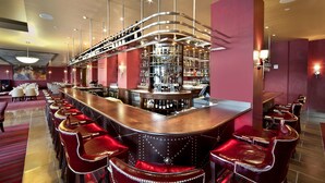 A bar area with a curved counter, red bar stools, and a well-stocked shelf with bottles. - Northern Hotel (Billings)