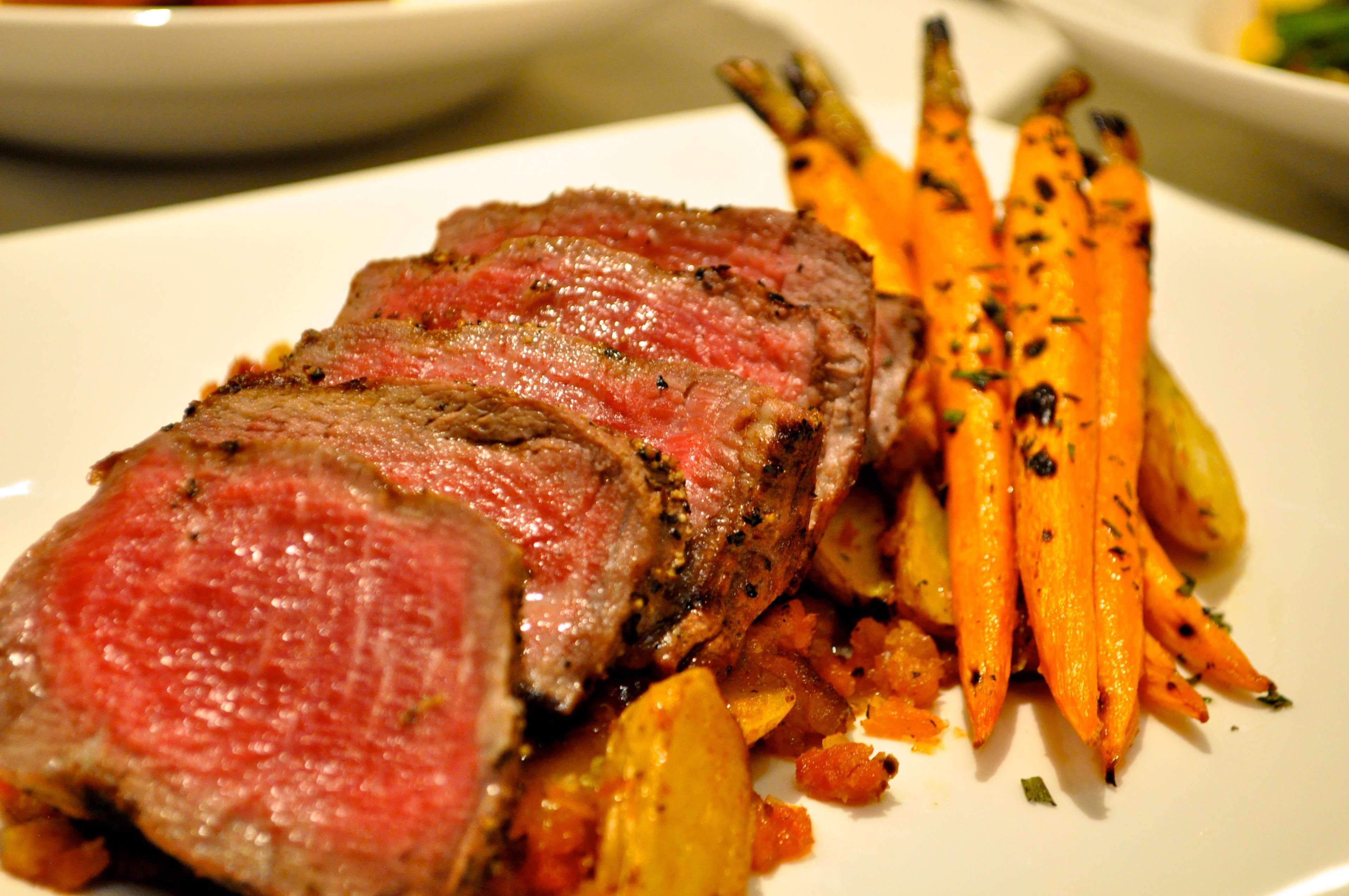 Un plato con filete en rodajas y zanahorias asadas.