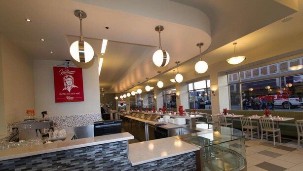 A modern restaurant interior with a curved counter, multiple dining tables, and hanging pendant lights. - Northern Hotel (Billings)