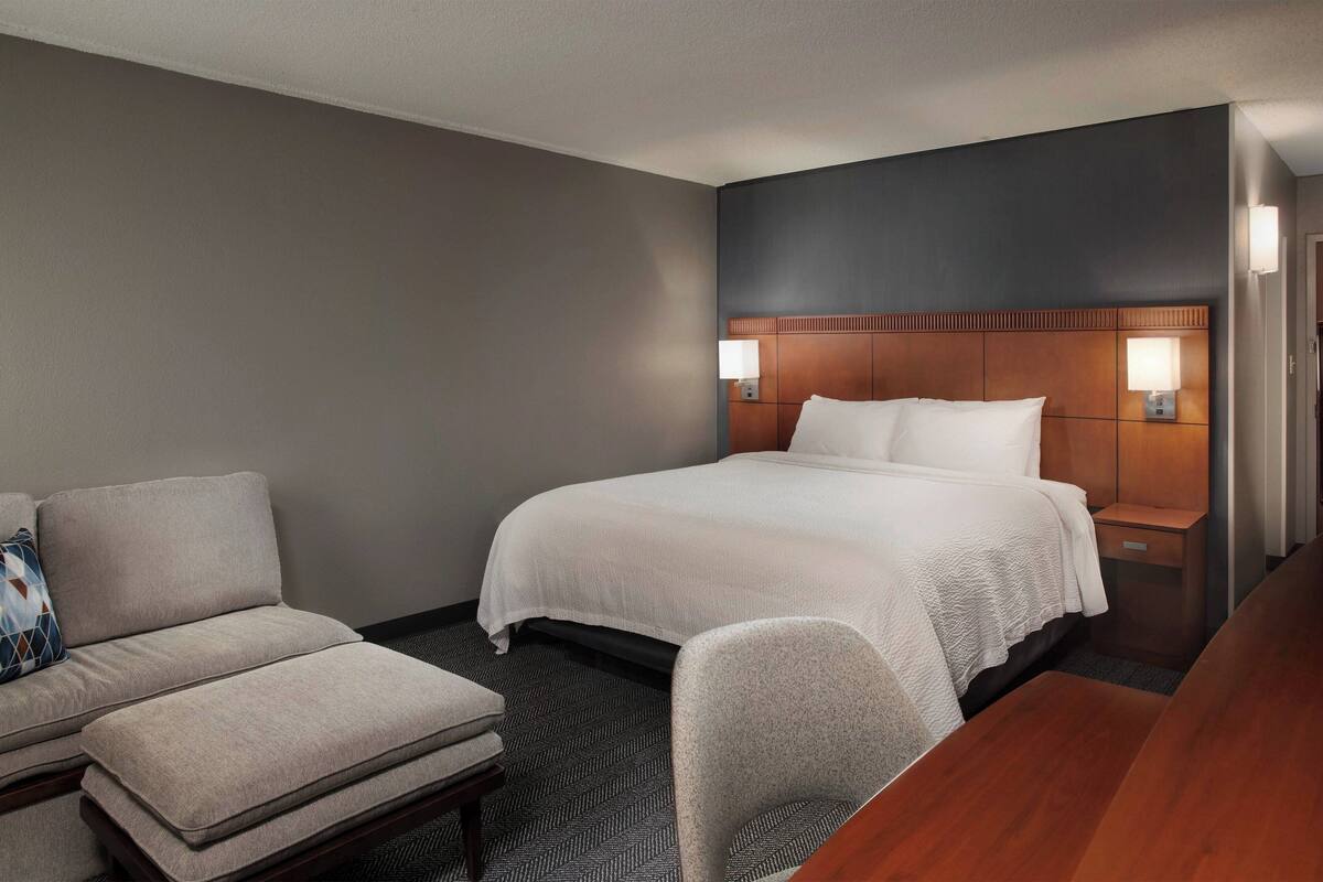 A hotel room with a bed, a sofa, a chair, and a desk.