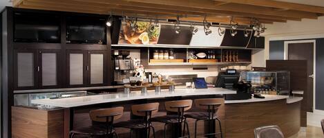A modern kitchen with a bar area, bar stools, and a counter with a coffee machine.