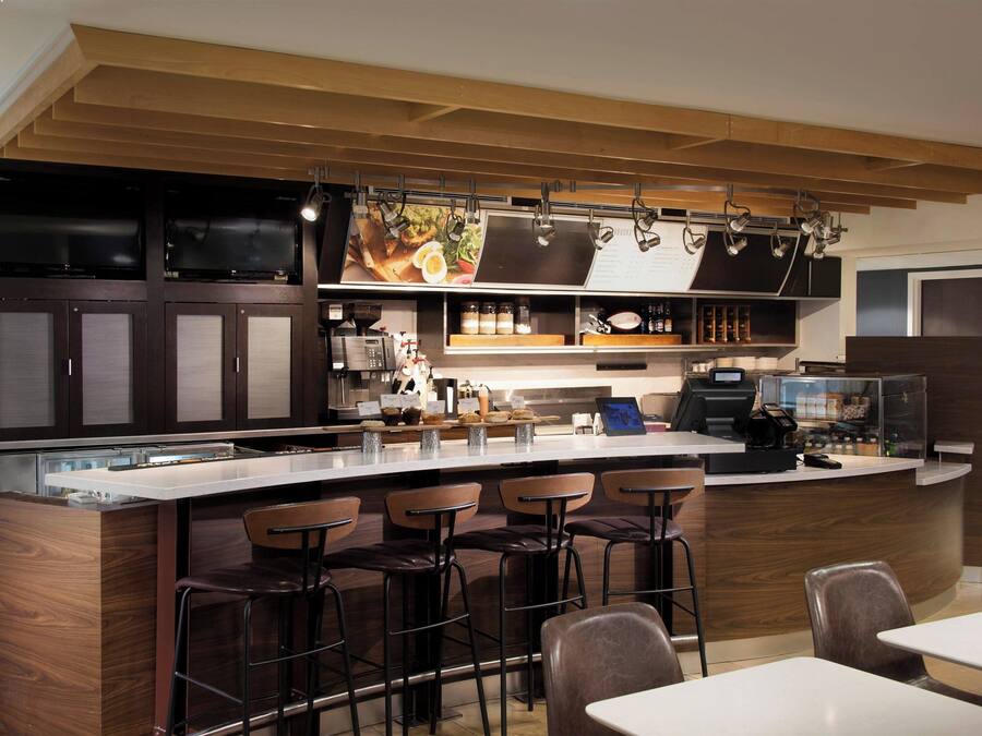 Cozinha moderna com área de bar, banquetas e balcão com máquina de café.