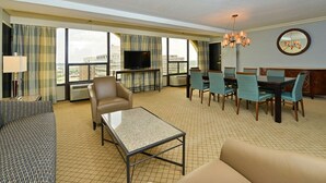 Ein Hotelzimmer mit Wohnbereich, Essbereich und Fernseher.