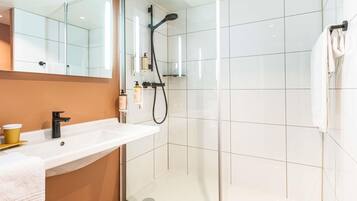 A modern bathroom with a glass shower enclosure, a white sink with a gold cup, and a towel rack.
