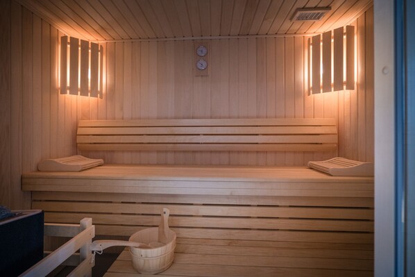 A wooden sauna with benches and a wooden bucket. - Mercure Mulhouse Centre (Mulhouse)