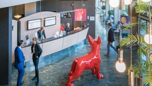 A lobby with a reception desk, a red sculpture, and a large colorful artwork on the wall.