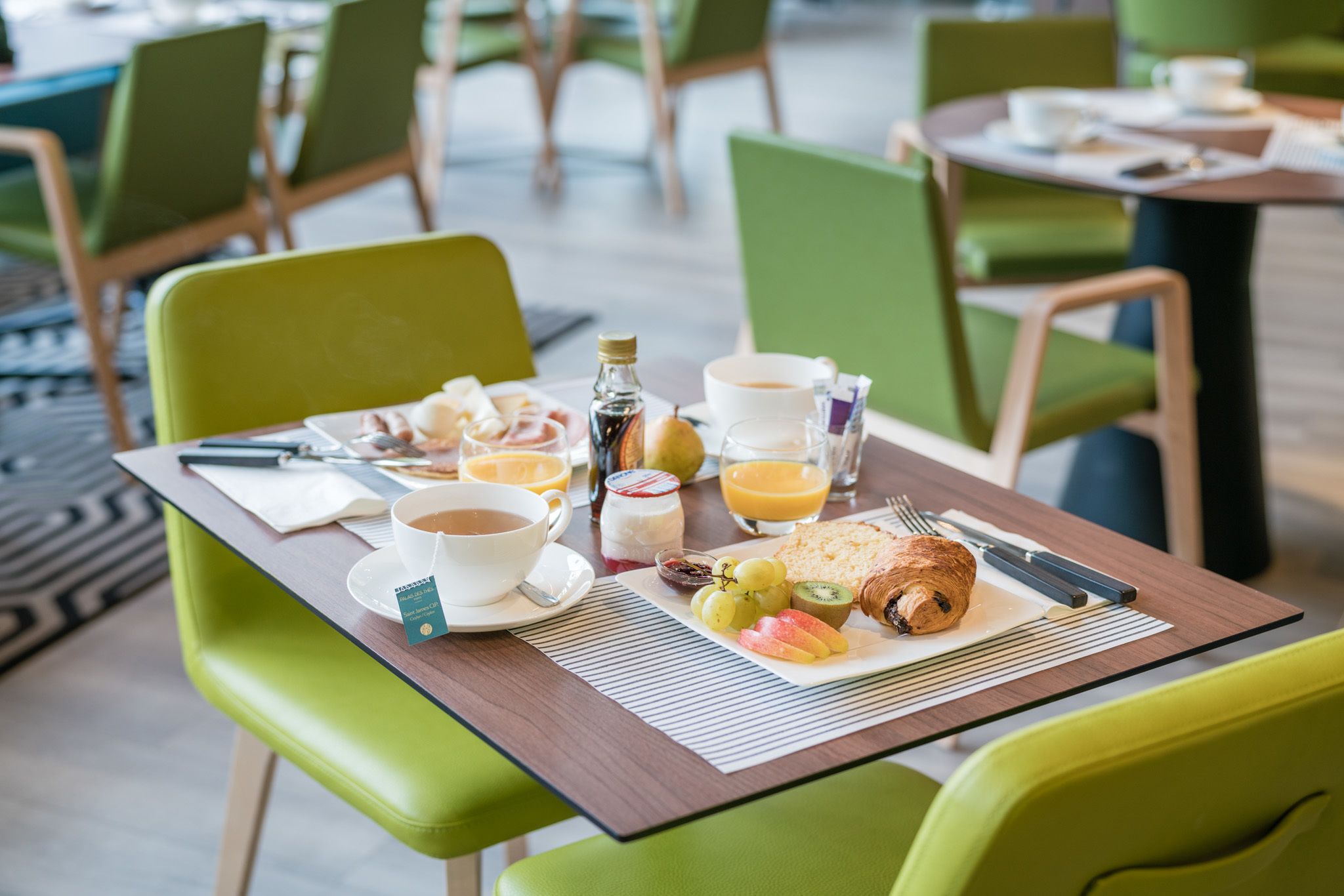 A breakfast table with a croissant, fruit, coffee, and juice.