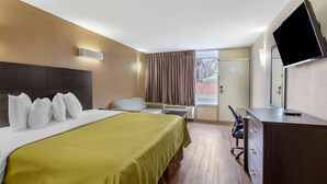 A hotel room with a large bed, a desk, a chair, a television, and a window with curtains. - Econo Lodge Roanoke Civic Center (Roanoke)